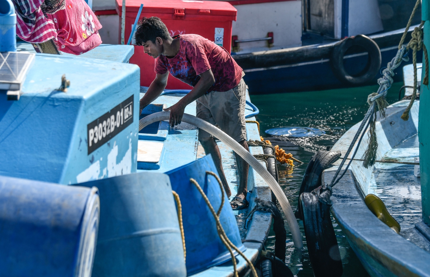 މަސް މާރުކޭޓް ސަރަހައްދު ފަޅުތެރޭ އަޅާފައިވާ ދޯންޏެއްގައި ހުރި މީހަކު މޫދަށް ހޮޅިއެއް ގުޅައިގެން މަސް ވަތަށް ލޮނު އަޅަނީ. -- ފޮޓޯ: ނިޝާން އަލީ/މިހާރު