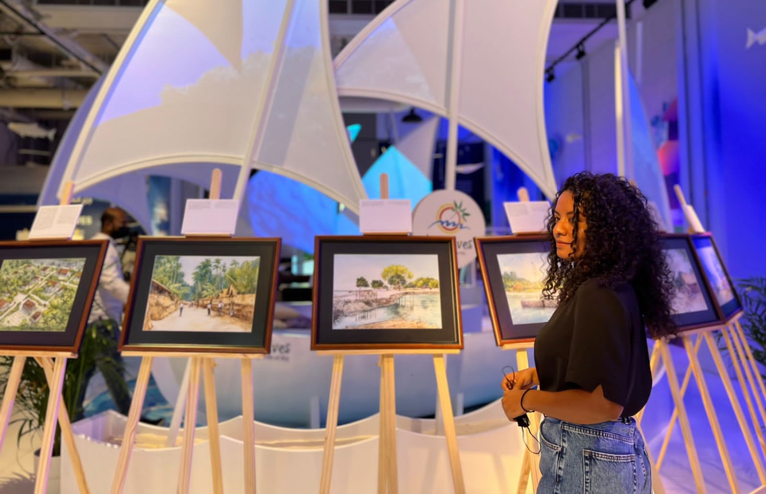 ދުބާއީ އެކްސްޕޯ 2020 ގައި ބޭއްވި އައިމިނަތު ޝިމްހާ ޝަކީބްގެ "މާލޭގެ ކިއްލާ" އާޓް އެގްޒިބިޝަންގައި ޝިމްހާ އޭނާގެ އާޓްވޯކްތައް ކައިރީގައި ހުއްޓިލައިގެން.-- ފޮޓޯ: ޝިމްހާ