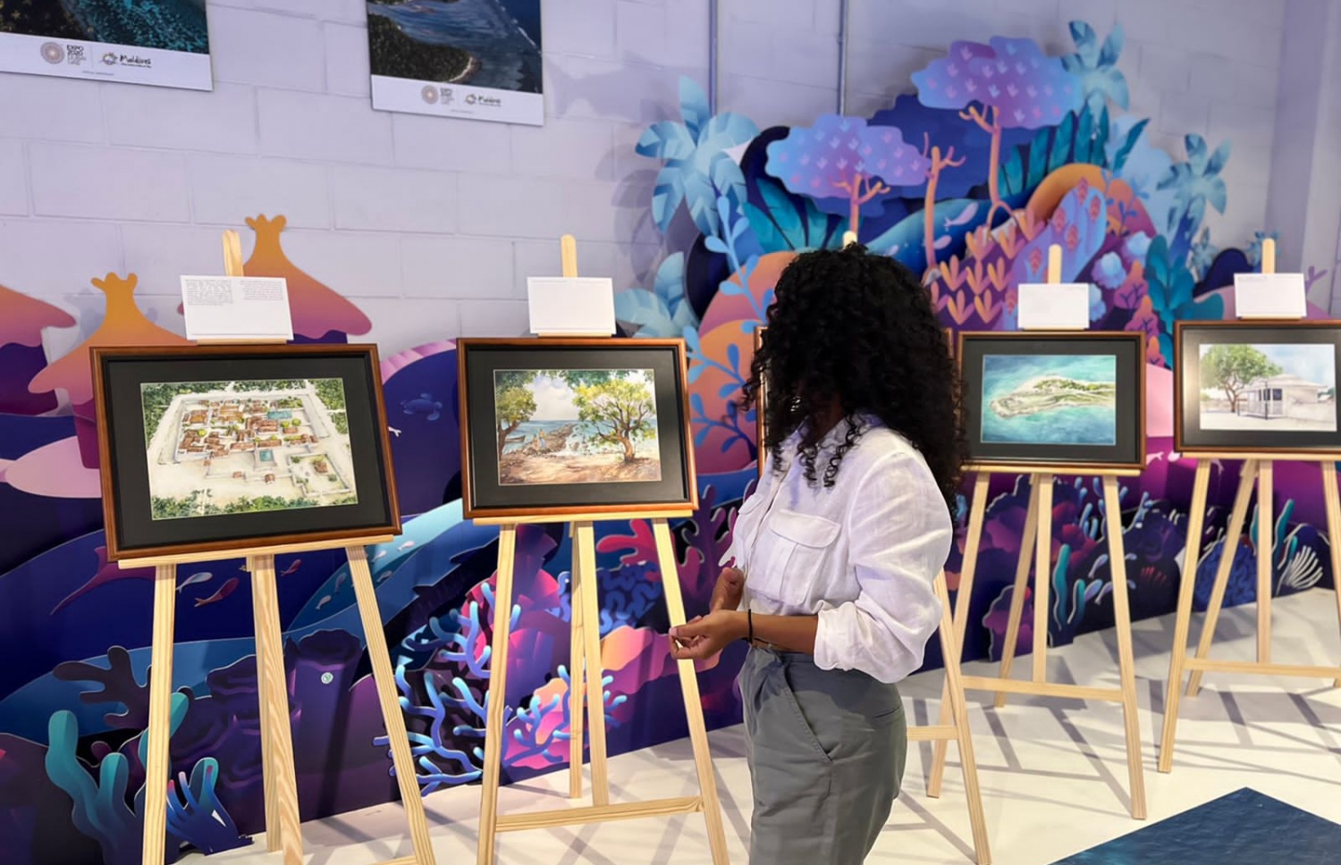 ދުބާއީ އެކްސްޕޯ 2020 ގައި ބޭއްވި އައިމިނަތު ޝިމްހާ ޝަކީބްގެ "މާލޭގެ ކިއްލާ" އާޓް އެގްޒިބިޝަންގައި ޝިމްހާ އޭނާގެ އާޓްވޯކްތައް ކައިރީގައި ހުއްޓިލައިގެން.-- ފޮޓޯ: ޝިމްހާ