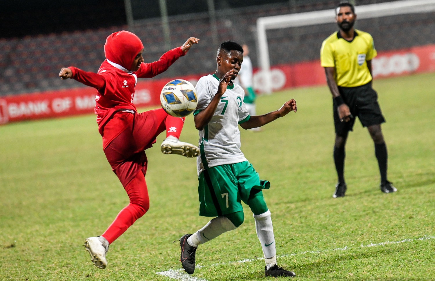 ރާއްޖެ އާއި ސައުދީ ކުޅުނު މެޗުގައި ރާއްޖޭގެ ކުޅުންތެރިން ސައުދީ ގޯލަށް ބޯޅަ ފޮނުވާލަން މަސައްކަތްކުރާއިރު ސައުދީ ކުޅުންތެރިއާ ހުރަސްއަޅަނީ --- ފޮޓޯ: ފަޔާޒު މޫސާ / މިހާރު