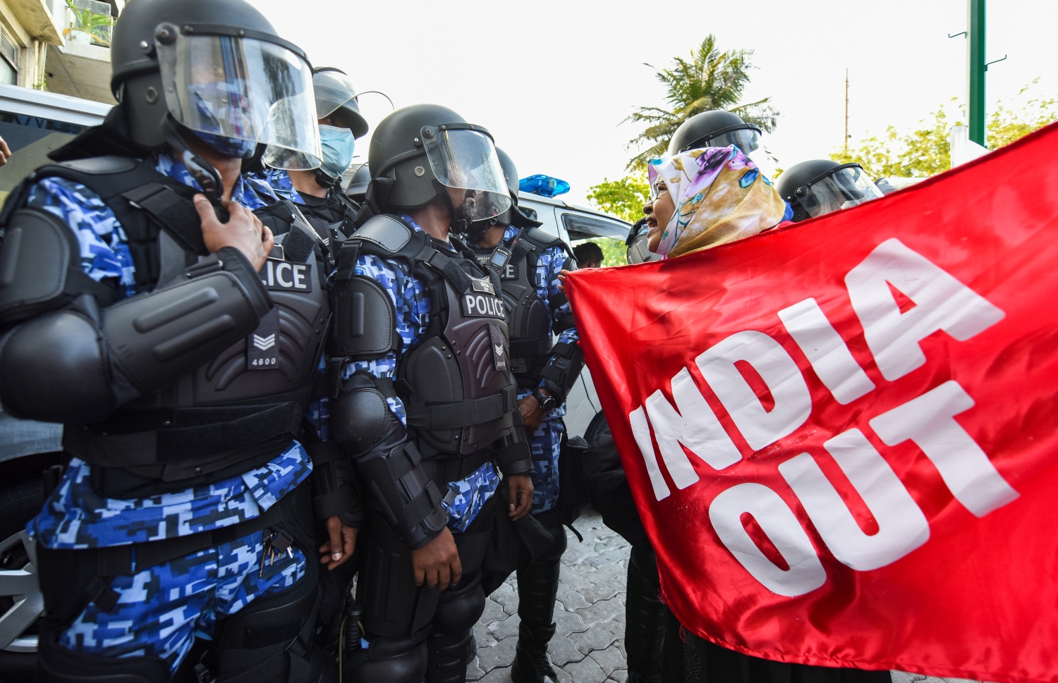 މަސްވެރިންގެ ޕާކް ސަރަހައްދުގައި މުޒާހަރާގެ ބައިވެރިއަކު "އިންޑިއާ އައުޓް" ލިޔެފައި ވާ ފޮތިގަނޑެއްހިފައިގެން ފުލުހުންގެ ސަފުތައްކައިރީ މުޒާހަރާކުރަނީ -- ފޮޓޯ: ފަޔާޒު މޫސާ / މިހާރު