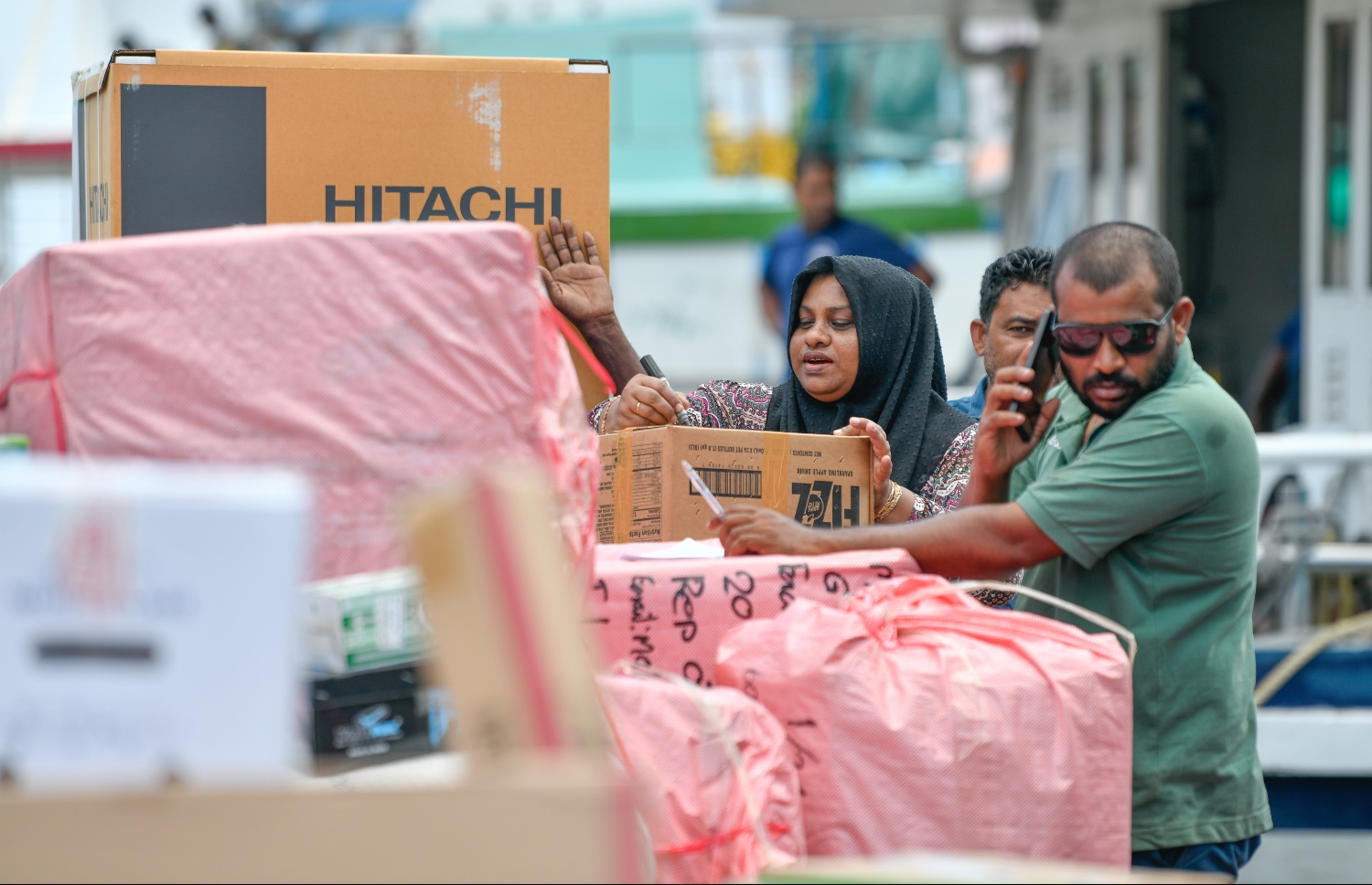 ނޯތު ހާބަރު ސަރަހައްދުގައި ތިބި ބަޔަކު ރަށަކަށް މުދާ ފޮނުވުމަށް ފޮށިގަނޑުތަކުގައި ނަން ޖަހަައި ބޯޓަށް އަރުވަން ތައްޔާރުކުރަނީ: ރޯދަ މަހުގެ ތައްޔާރީތަކާ އެކު، މާލޭގެ ބާޒާރުމަތީގެ ސަރަހައްދު ވަނީ ވަރަށް ބޮޑަށް ހަލަބޮލިވެފައި.-- ފޮޓޯ: ނިޝާން އަލީ | މިހާރު