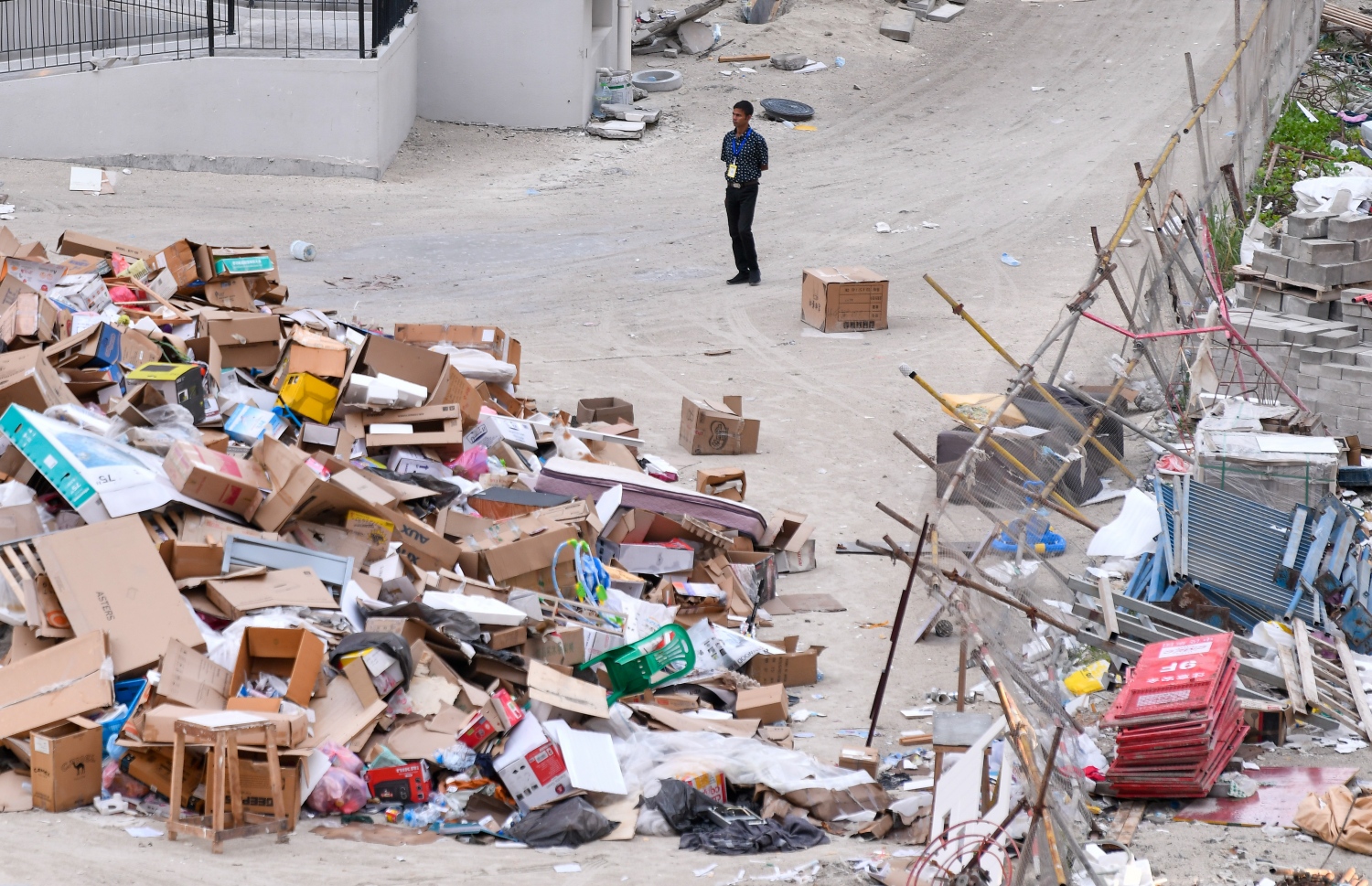 އެޗް 1 އަދި 2 ވަނަ ޓަވަރުގެ މެދަށް ޖަމާކޮށްފައި ހުރި ކުނިތަކެއްގެ ކައިރީގައި އެ ސަރަހައްދުގެ ފްލެޓްތަކުގެ ސެކިއުރިޓީ ބަލަހައްޓާ މީހަކު މަޑުކޮށްލައިގެން.--- ފޮޓޯ: ފަޔާޒު މޫސާ | މިހާރު