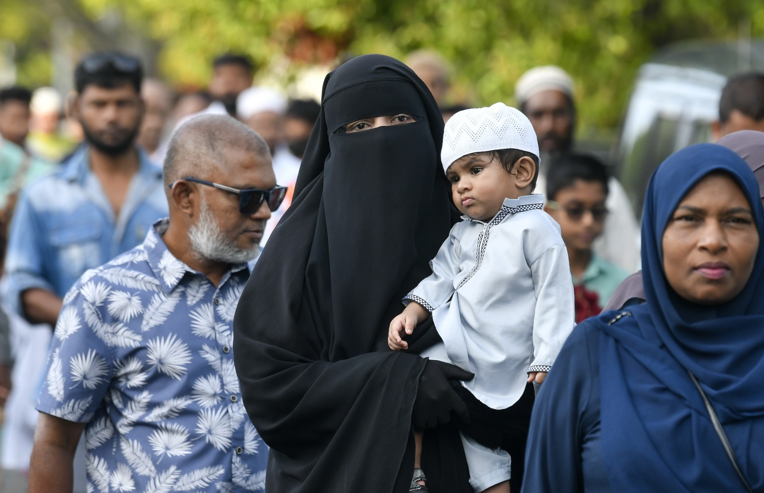 ހުޅުމާލޭގެ ސްޓޭޑިއަމް ސަރަހައްދުގައި ހެދި ބޮޑު ޖަމާއަތަށް ފިތުރު އީދު ނަމާދަށް ދިޔަ އަންހެނަކު ކުޑަކުއްޖަކު އުރާލައިގެން ދަނީ: ދެ އަހަރުގެ މެދުކެނޑުމަކަށް ފަހު އީދު ނަމާދު ކުރުމުން ގިނަ ބަޔަކު އެ އަޅުކަމުގައި ބައިވެރިވި.---ފޮޓޯ: ނިޝާން އަލީ| މިހާރު