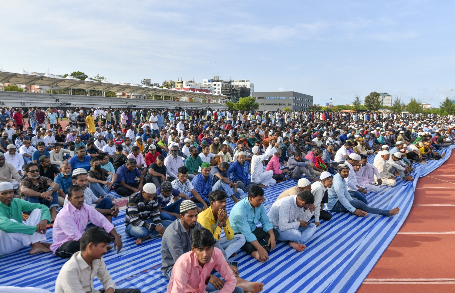 ހުޅުމާލޭގެ ސްޓޭޑިއަމް ސަރަހައްދުގައި ހެދި ބޮޑު ޖަމާއަތަށް ފިތުރު އީދު ނަމާދަށް ދިޔަ މީހުން އިށީނދެގެން: ދެ އަހަރުގެ މެދުކެނޑުމަކަށް ފަހު އީދު ނަމާދު ކުރުމުން ގިނަ ބަޔަކު އެ އަޅުކަމުގައި ބައިވެރިވި.---ފޮޓޯ: ނިޝާން އަލީ| މިހާރު