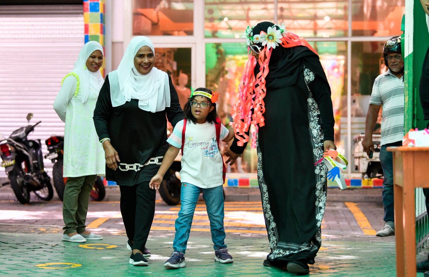 ގަލޮޅު ސްކޫލުގެ އަހަރީ ދުވަހާއި ކުޑަކުދިންގެ ދުވަހުގެ ހަރަކާތްތަކުގައި ބައިވެރިވި ކުއްޖަކަށް ޕްރިންސިޕަލް ސުރައްޔާ (ވ) އާއި އެހެން ޓީޗަރަކު މަރުހަބާ ކިޔަނީ: ޕްރިންސިޕަލާއި ޓީޗަރުންގެ ފަރާތުން ކުދިންނަށް ހާއްސަ މަރުހަބާއެއް ކިޔާފައިވޭ.---ފޮޓޯ: ފަޔާޒު މޫސާ| މިހާރު