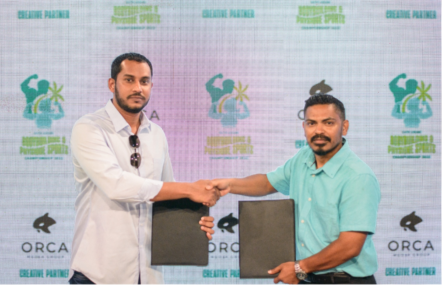 އަންނަ މަހު ރާއްޖޭގައި ބާއްވާ އޭޝިއާގެ ބޮޑީ ބިލްޑިން ޗެމްޕިއަންޝިޕްގެ ކްރިއޭޓިވް ޕާޓްނަރެއްގެ ގޮތުގައި ހަމަޖަެއްސި އޯކާ މީޑިއާ ގުރޫޕްގެ ސީއޯއޯ ނާސިރު (ވ) އާއި ބީބީއޭއެމްގެ ނައިބު ރައީސް އައިމަން (ވ) އެއްބަސްވުމުގައި ސޮއި ކުރުމަށް ފަހު އެއްބަސްވުން ދައްކާލަނީ --- ފޮޓޯ: ޒިދާން ހުސައިން | ބީބީއޭއެމް