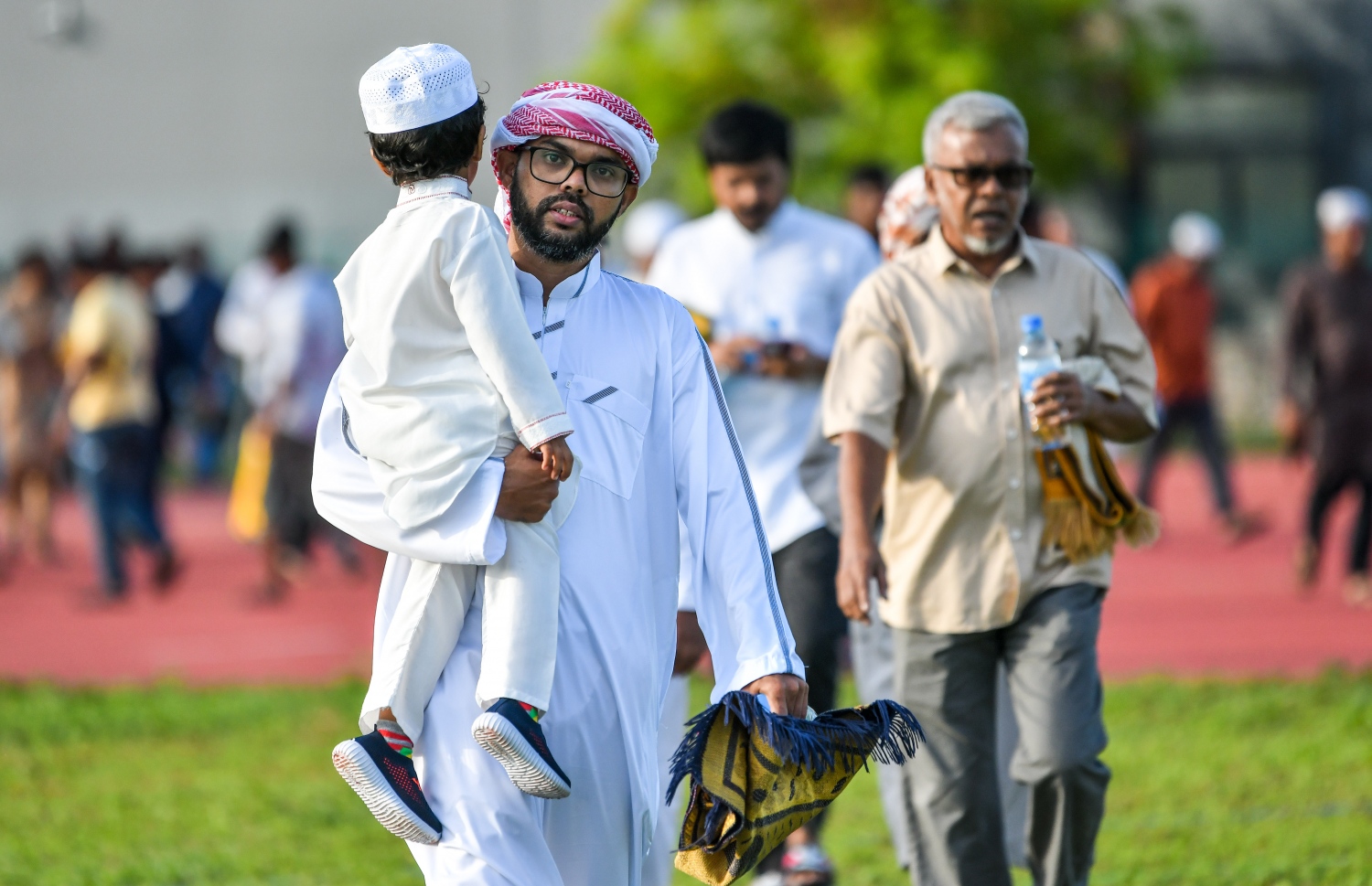 ޖުލައި 9، 2022 - ހުޅުމާލެ: އީދު ނަމާދުގެ ބޮޑު ޖަމާއަތަށް ދިޔަ މީހަކު ކުއްޖަކު އުރާލައިގެ. ނަމާދުގައި ހުރިހާ އުމުރެއްގެ މީހުން ބައިވެރިވި. -- ފޮޓޯތައް: ފަޔާޒް މޫސާ/މިހާރު