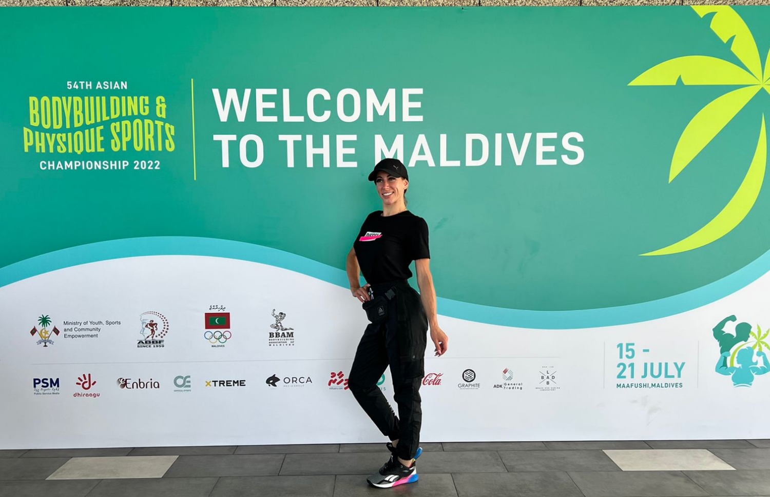 ރާއްޖޭގައި ބާއްވާ 54 ވަނަ އޭޝިއަން ބޮޑީބިލްޑިންގް ޗެމްޕިއަންޝިޕްގައި ވާދަކުރަން އައި ކަޒަކިސްތާނުގެ އެތުލީޓަކު، މުބާރާތް ޕްރޮމޯޓް ކުރަން ވެލާނާ އިންޓަނޭޝަނަލް އެއާޕޯޓުގައި ހަރުކޮށްފައިވާ ބިލްބޯޑް ކައިރީގައި ފޮޓޯއަކަށް ހުއްޓިގެން.--- ފޮޓޯ: ބީބީއޭއެމް