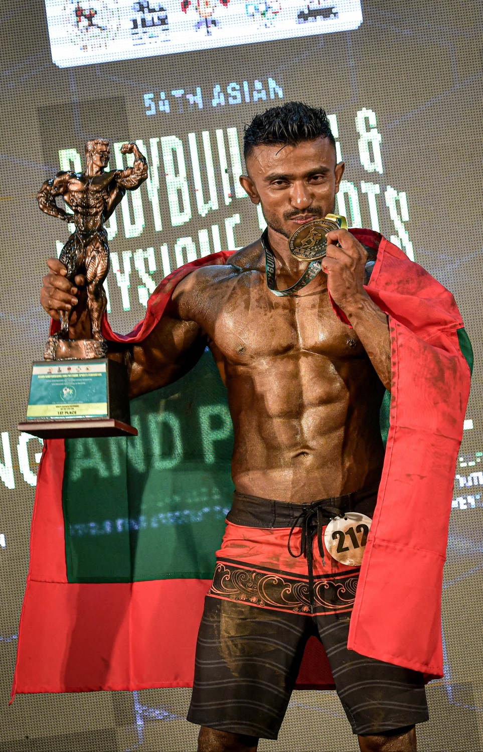 ރާއްޖޭގައި މިއަދު ފެށި އޭޝިއާގެ ބޮޑީ ބިލްޑިން މުބާރާތުގެ ސްޕޯޓް ފިޒިކް 170 ސީއެމް ކެޓަގަރީން 1 ވަނަ ހޯދި ދިވެހި އެތުލީޓް އަޒުނީން ރަޝާދު ރަންމެޑަލްގެ އުފާ ފާހަގަކުރަނީ.--- ފޮޓޯ: ނިޝާން އަލީ/މިހާރު