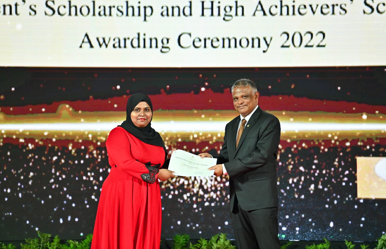 ރައީސް ދެއްވާ ހާއްސަ ސްކޮލަޝިޕާއި ހައި އެޗީވާސް ސްކޮލަޝިޕްގެ ލިޔުން ހަވާލު ކުރުމަށް ގިޔާސުއްދީން ސްކޫލުގައި ބޭއްވި ހަފުލާގައި ހަޔާ އެޑިއުކޭޝަން ޑރ. މިނިސްޓަރު އިބްރާހިމް ހަސަން، ހައި އެޗީވާސް ސްކޮލަޝިޕް ލިބުނު ދަރިވަރަކަށް ލިޔުން ހަވާލު ކުރައްވަނީ.-- ފޮޓޯ: ރައީސް އޮފީސް