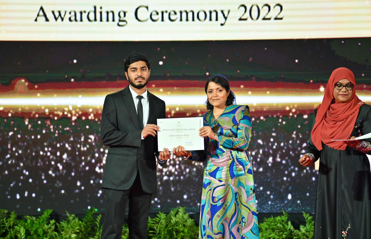 ރައީސް ދެއްވާ ހާއްސަ ސްކޮލަޝިޕާއި ހައި އެޗީވާސް ސްކޮލަޝިޕްގެ ލިޔުން ހަވާލު ކުރުމަށް ގިޔާސުއްދީން ސްކޫލުގައި ބޭއްވި ހަފުލާގައި އާޓްސް އެންޑް ހެރިޓޭޖް މިނިސްޓަރު ދުންޔާ މައުމޫން، ހައި އެޗީވާސް ސްކޮލަޝިޕް ލިބުނު ދަރިވަރަކަށް ލިޔުން ހަވާލު ކުރައްވަނީ.-- ފޮޓޯ: ރައީސް އޮފީސް