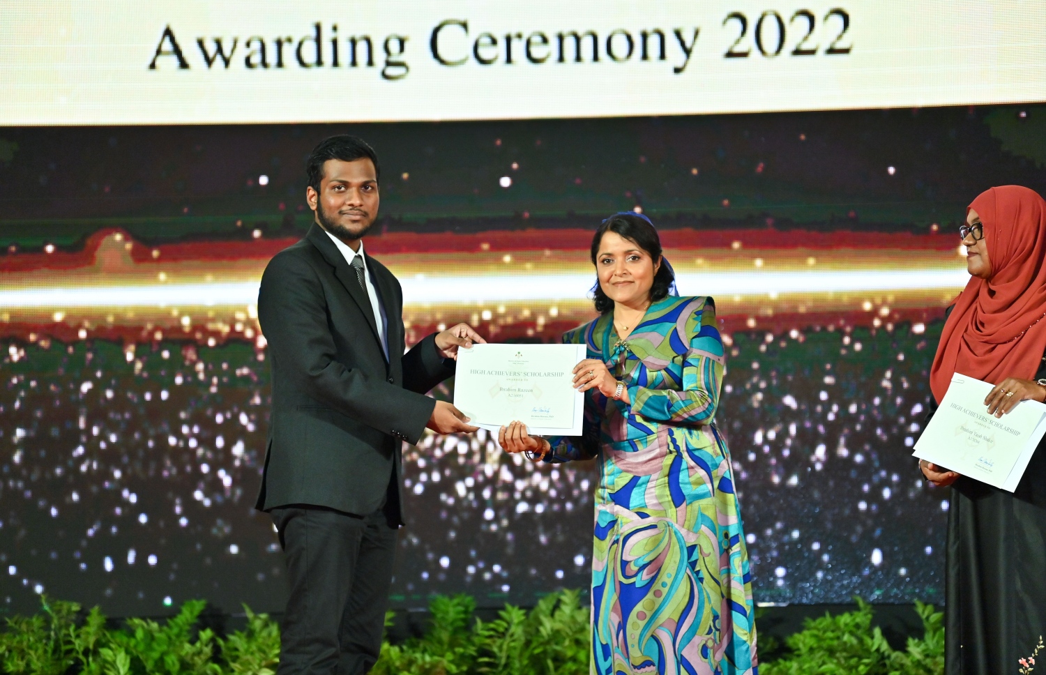 ރައީސް ދެއްވާ ހާއްސަ ސްކޮލަޝިޕާއި ހައި އެޗީވާސް ސްކޮލަޝިޕްގެ ލިޔުން ހަވާލު ކުރުމަށް ގިޔާސުއްދީން ސްކޫލުގައި ބޭއްވި ހަފުލާގައި އާޓްސް އެންޑް ހެރިޓޭޖް މިނިސްޓަރު ދުންޔާ މައުމޫން، ހައި އެޗީވާސް ސްކޮލަޝިޕް ލިބުނު ދަރިވަރަކަށް ލިޔުން ހަވާލު ކުރައްވަނީ.-- ފޮޓޯ: ރައީސް އޮފީސް