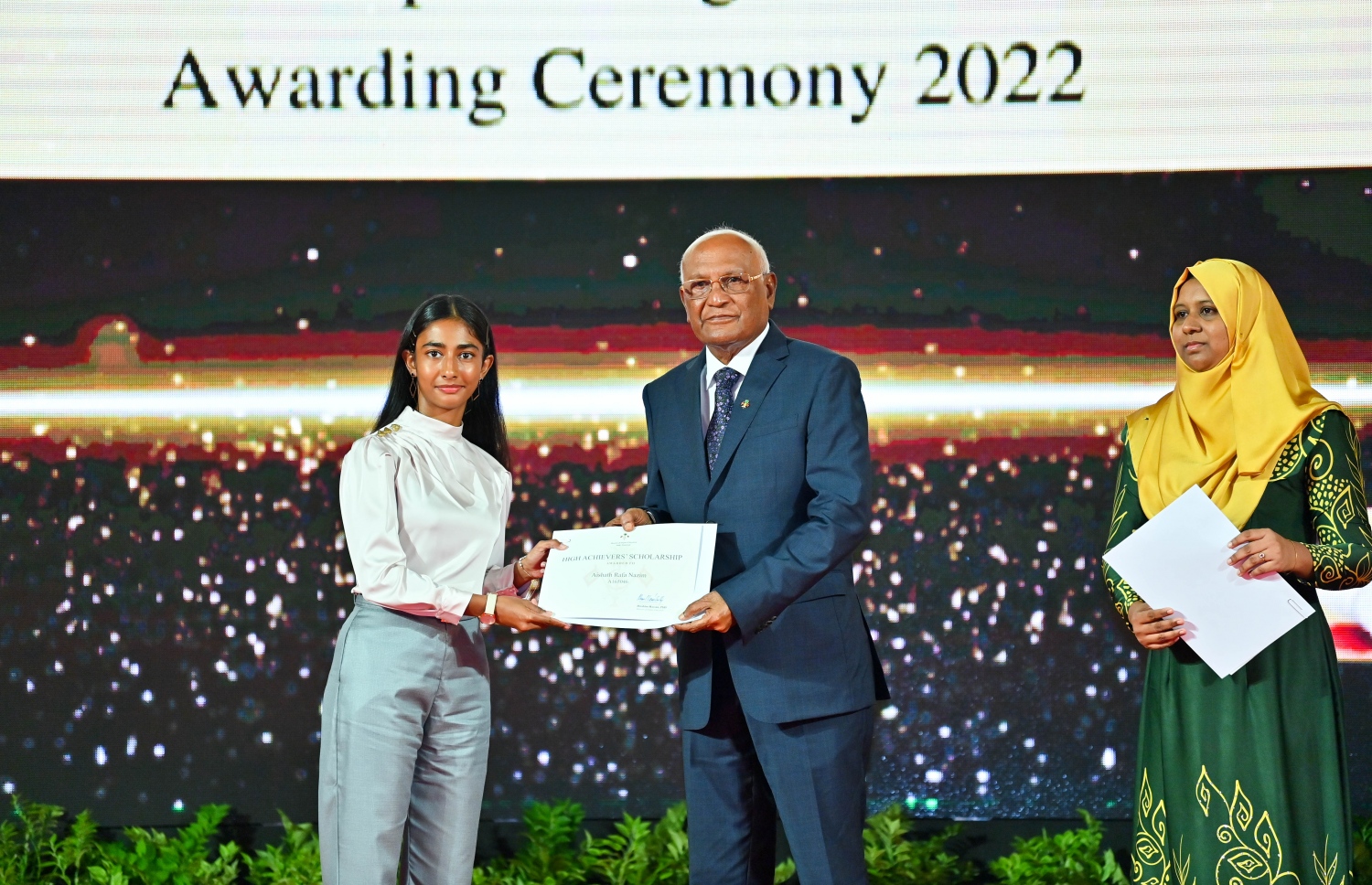 ރައީސް ދެއްވާ ހާއްސަ ސްކޮލަޝިޕާއި ހައި އެޗީވާސް ސްކޮލަޝިޕްގެ ލިޔުން ހަވާލު ކުރުމަށް ގިޔާސުއްދީން ސްކޫލުގައި ބޭއްވި ހަފުލާގައި ހެލްތު މިނިސްޓަރު އަހުމަދު ނަސީމް، ހައި އެޗީވާސް ސްކޮލަޝިޕް ލިބުނު ދަރިވަރަކަށް ލިޔުން ހަވާލު ކުރައްވަނީ.-- ފޮޓޯ: ރައީސް އޮފީސް