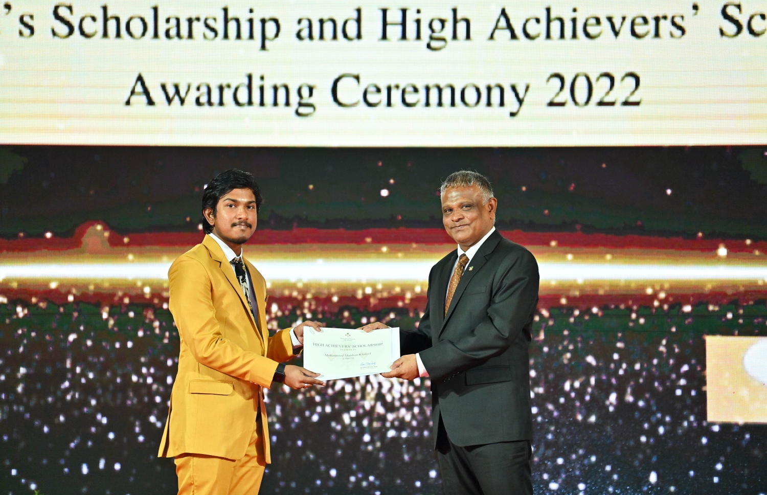 ހައި އެޗީވާސް ސްކޮލަޝިޕް ލިބުނު ދަރިވަރަކަށް، ހަޔަ އެޑިއުކޭޝަން މިނިސްޓަރު ޑރ. އިބްރާހިމް ހަސަން ރޭ ލިޔުން ހަވާލުކޮށްދެއްވަނީ.-- ފޮޓޯ: ރައީސް އޮފީސް