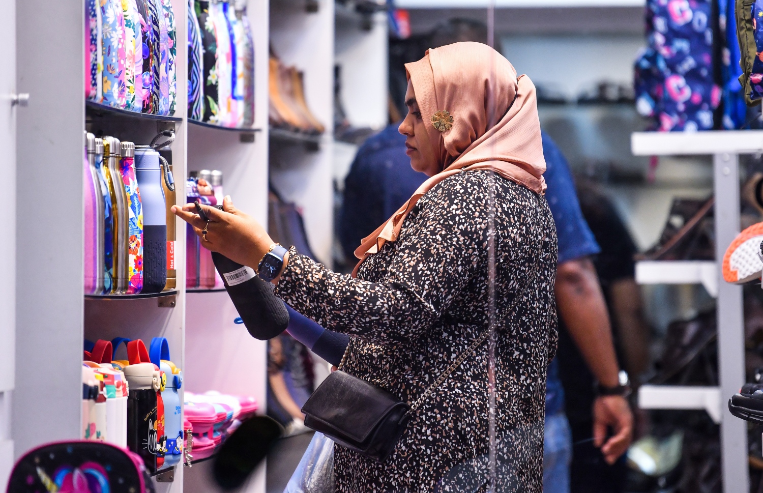 ފިހާރައެއްގައި ވިއްކަން ހުރި ފެން އަޅާ ފުޅިތަކެއް މީހަކު ބަލާލަނީ: އެއްފަހަރު ބޭނުންކުރެވޭ ޕްލާސްޓިކް ފުޅީގެ ބަދަލުގައި މިހާރު ގެންދެވެނީ މި ފަދަ ފުޅި -- ފޮޓޯ: ފަޔާޒު މޫސާ | މިހާރު