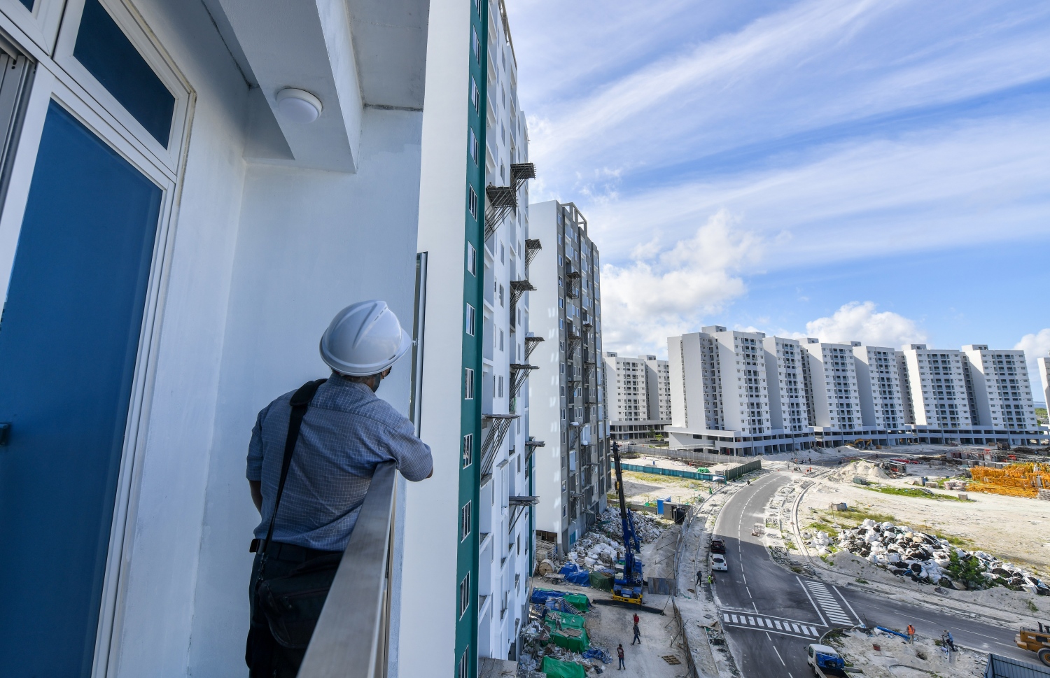 އެމްޕީއެލް ފްލެޓްގެ ބެލްކަނީގައި މީހަކު ބޭރު ބަލާލަނީ: މި ފްލެޓްތައް އިމާރާތްކޮށްފައި ވަނީ 15 ބުރީގެ ތިން ޓަވަރު، އެތަނުގައި 534 އެޕާޓްމެންޓް ހަދާފައިވޭ. އެއީ އެއް ރޫމްގެ 204 އެޕާޓްމެންޓާއި 1+2 ރޫމްގެ 330 އެޕާޓްމެންޓެވެ -- ފޮޓޯ: ފަޔާޒު މޫސާ | މިހާރު