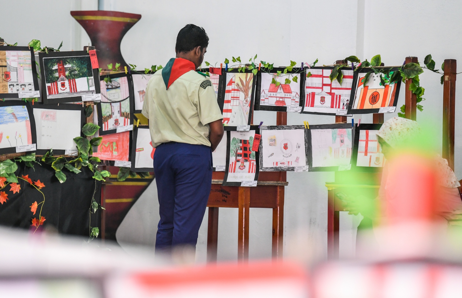 "މައި މަޖީދިއްޔާ-ތްރޫ ދި މައިންޑްސް އެންޑް ހޭންޑް އޮފް މަޖީދިއަންސް" ގެ ނަމުގައި ބޭއްވި މައުރަޒުގައި ހުރި ކުރެހުންތައް އެ ސްކޫލްގެ ސްކައުޓު ކުއްޖަކު ބަލަނީ.--- ފޮޓޯ: ފަޔާޒު މޫސާ | މިހާރު