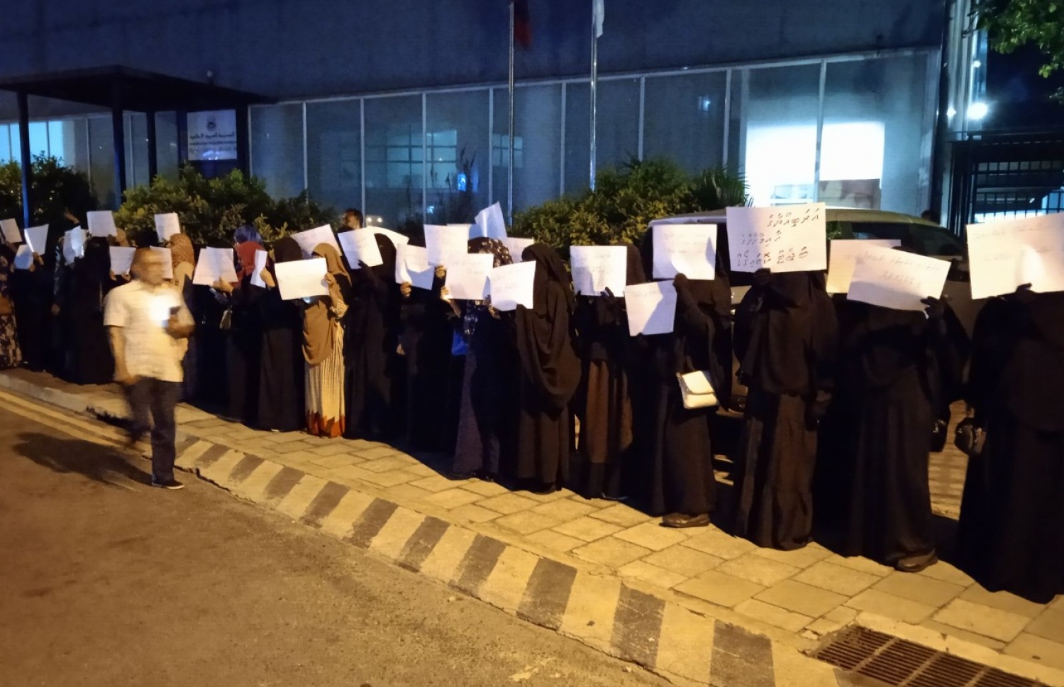 އެކި ޝުއޫރުތައް ލިޔެފައިވާ ޕޯސްޓަރުތައް ހިފައިގެން އަރަބިއްޔާ ސްކޫލުގެ ބެލެނިވެރިން ސްކޫލުގެ ބޭރުގައި މުޒާހަރާކުރަނީ.