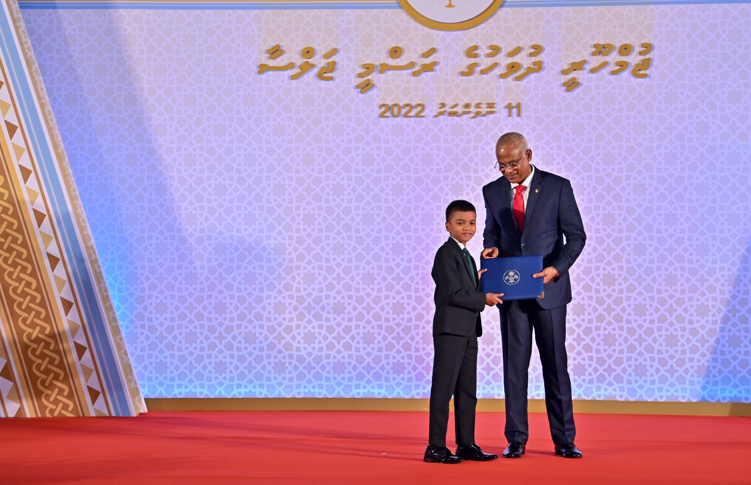 ކީރިތި ގުރްއާން ހިތުދަސްކޮށް އެއްވަނަ ދަރަޖައިގައި ފާސްވި ހާފިޒް އުމުރުން އަށް އަހަރުގެ އަމަން އަހުމަދު އާތިފަށް، ދަރުބާރުގޭގައި ރޭ ބޭއްވި ޖުމްހޫރީ ދުވަހުގެ ރަސްމީ ޖަލްސާގައި ރައީސް އިބްރާހިމް މުހައްމަދު ސޯލިހް އިނާމް ދެއްވަނީ -- ފޮޓޯ: ރައީސް އޮފީސް