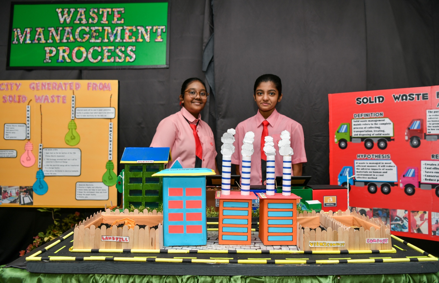 އިސްކަންދަރު ސްކޫލްގެ ސައިންސް ފެއާގައި ބައިވެރިކޮށްފައި ހުރި، ކުނި ނައްތާލުމުގެ މަސައްކަތް ދައްކުވައިދޭ އުފެއްދުމެއްގެ ކައިރީގައި ދެ ކުއްޖަކު މަޑުކޮށްލައިގެން: އެ ފެއާގައި އެ ސްކޫލްގެ ހުރިހާ ކުދިން ބައިވެރިވި.-- ފޮޓޯ: ފަޔާޒު މޫސާ | މިހާރު