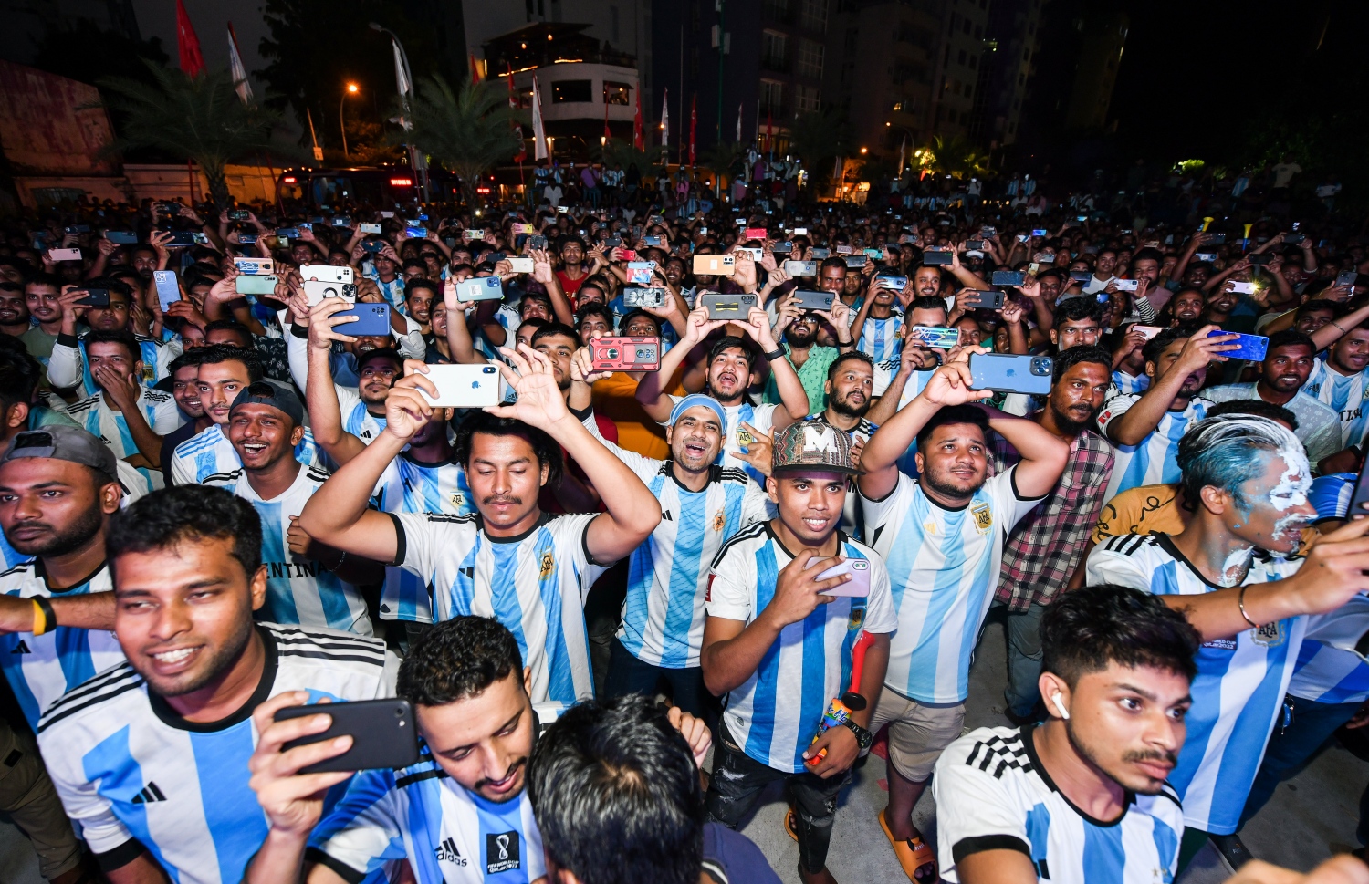 ވޯލްޑް ކަޕް މުބާރަތް ތިން ވަނަ ފަހަރަށް ކާމިޔާބު ކުރި އާޖެންޓީނާ އަށް ވޯލްޑް ކަޕް ތަށި ދޭން ތައްޔާރު ވާއިރު، މާލޭގެ އާޓީފިޝަލް ބީޗު ސަރަަހައްދުގައި ބޮޑު ސްކްރީނުން މެޗު ބަލަން ޖަމާވި މީހުން ފޯނުން އެ މަންޒަރުގެ ފޮޓޯ ނަގަނީ.--- ފޮޓޯ: ފަޔާޒު މޫސާ | މިހާރު