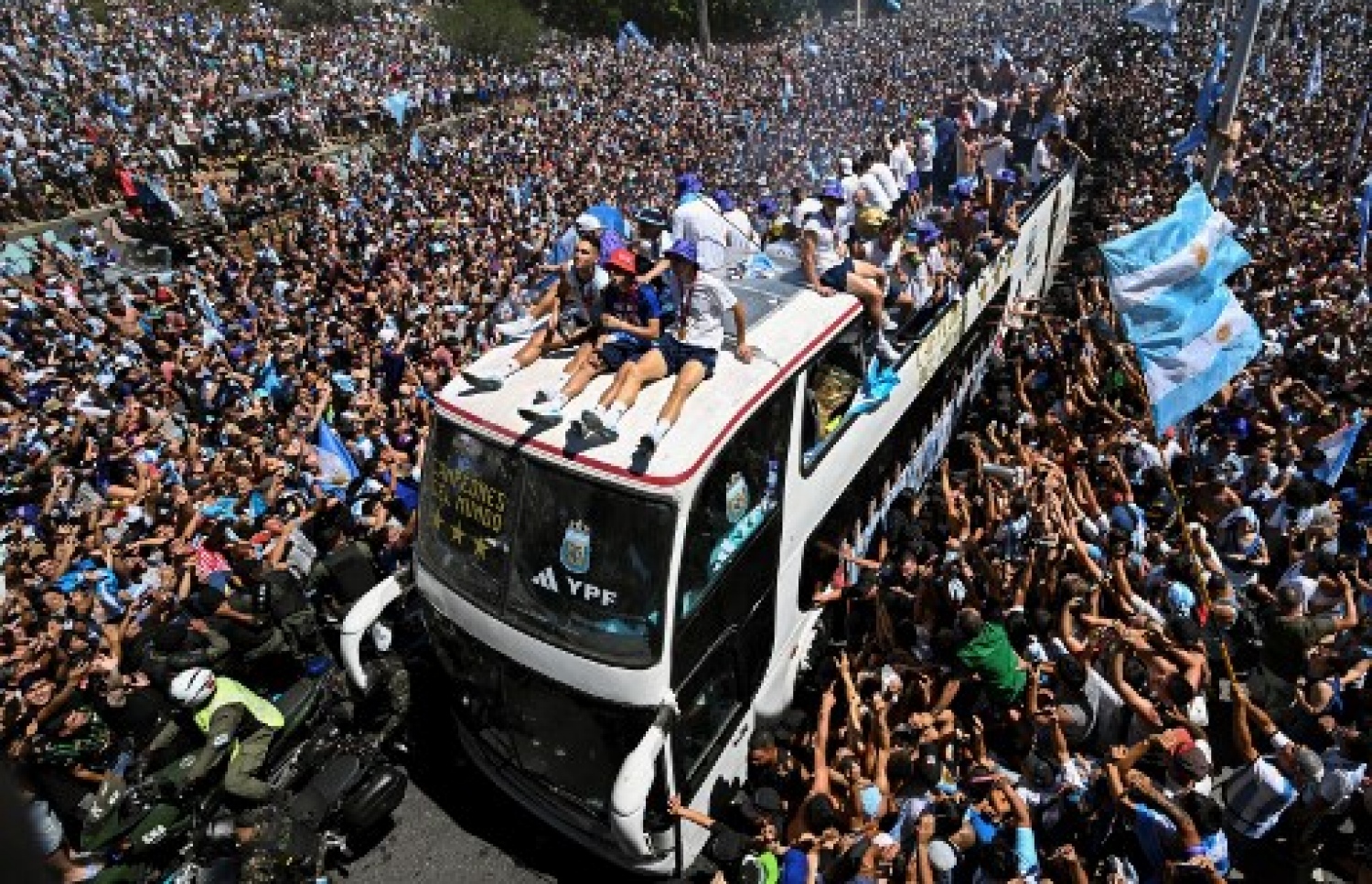 ވޯލްޑް ކަޕުގެ ތަށި ހިފައިގެން އާޖެންޓީނާ ކުޅުންތެރިން އެ ގައުމުގެ ވެރިރަށް ބީނޯސް އޭރީޒްގައި ބޭއްވި ބަސް ޕެރޭޑުގައި އާންމުން ބައިވެރިވެ އުފާފާޅުކުރަނީ: މިއީ އާޖެންޓީނާ ވޯލްޑް ކަޕް ތަށި އުފުލާލި ތިންވަނަ ފަހަރު.-- ފޮޓޯ: އޭއެފްޕީ