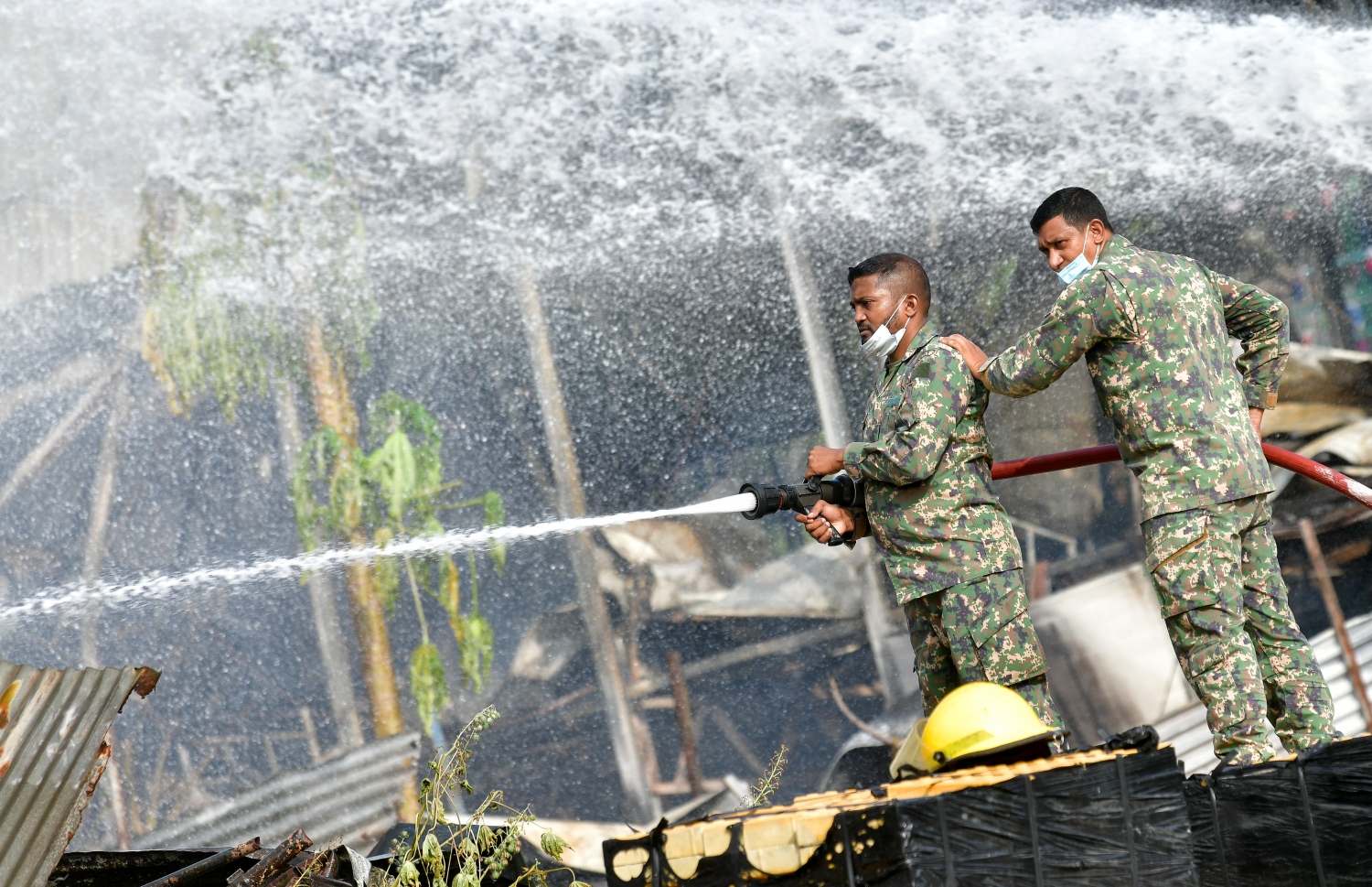 މާލޭގެ ދެކުނު ފަރާތު، ކުރީގެ އެއް ނަމްބަރު ކުނިކޮށި ހިމެނޭ "ނީލަން ފިހާރަ" އިގައި ރޯވުމުން އެމްއެންޑީއެފް އިން އަލިފާންގަނޑު ނިއްވާލުމަށް މަސައްކަތް ކުރަނީ.-- ފޮޓޯ: ނިޝާން އަލީ/ މިހާރު