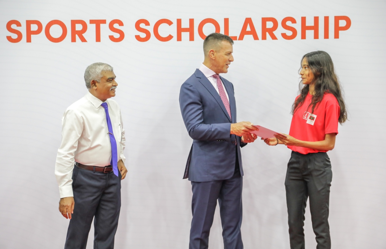 ސްކޮލާޝިޕް ލިބުނު އެތުލީޓަކަށް އެކަމުގެ ލިޔުން ދެނީ. --ފޮޓޯ:ބީއެމްއެލް