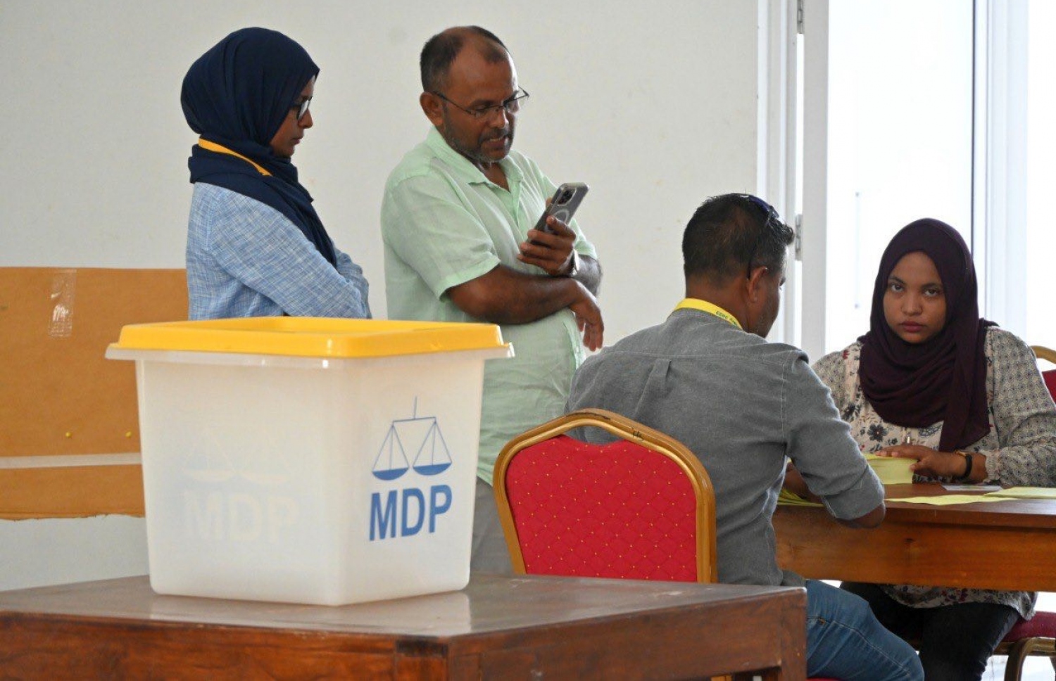 އެމްޑީޕީގެ ތާރީހުގައި ބާއްވާ އެންމެ ވާދަވެރި އެމްޑީޕީ ރިޔާސީ ޕްރައިމަރީގެ ވޯޓުލުމަށް އައްޑޫ، ހިތަދޫގައި ބަހައްޓާފައި ހުރި ވޯޓު ފޮއްޓަށް މީހަކު ވޯޓުލުމަށް އޮފިޝަލުން މޭޒު ކައިރީގައި.-- ފޮޓޯ: އަހުމަދު އިޝާމް