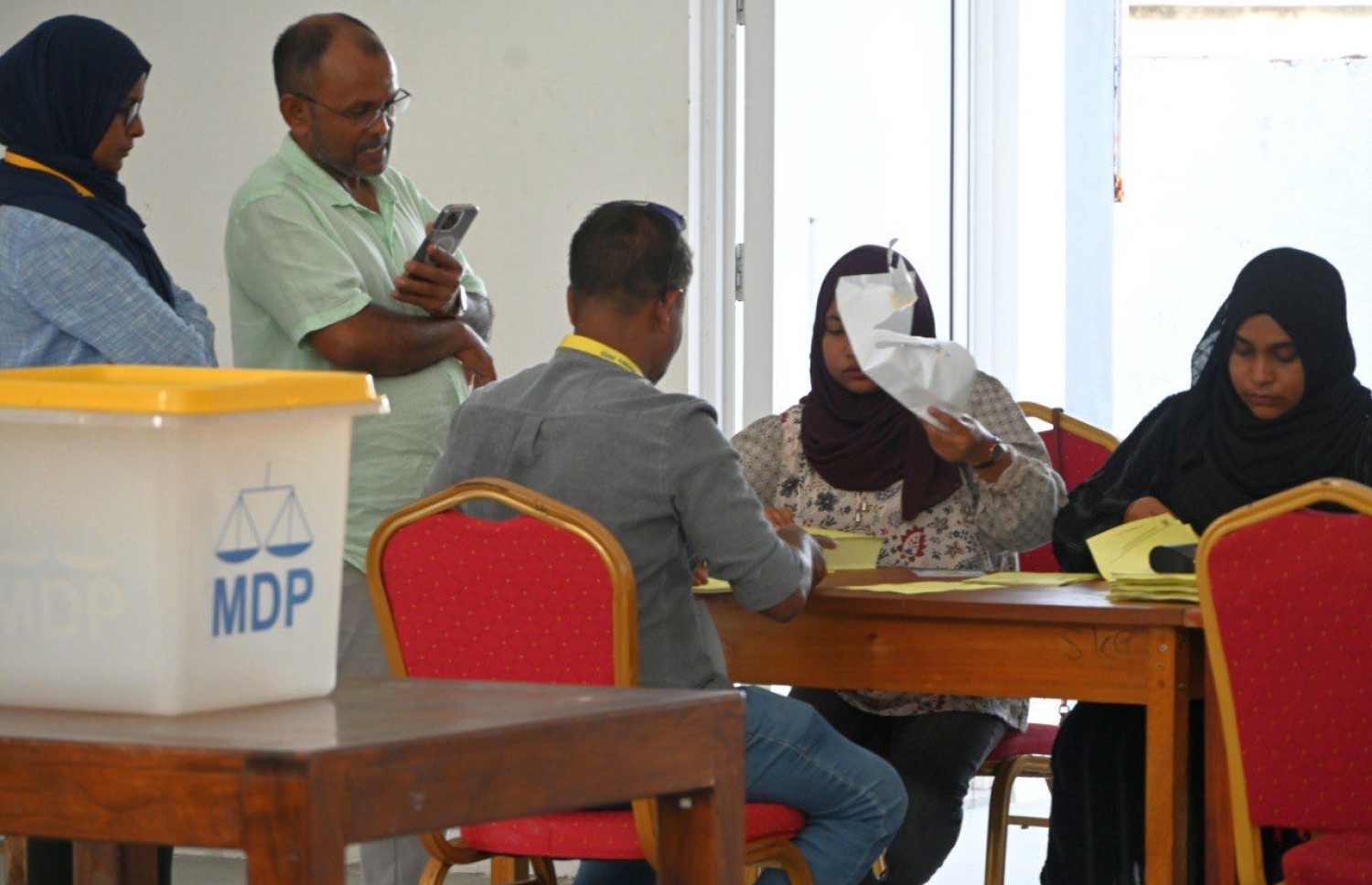 އެމްޑީޕީގެ ތާރީހުގައި ބާއްވާ އެންމެ ވާދަވެރި އެމްޑީޕީ ރިޔާސީ ޕްރައިމަރީގެ ވޯޓުލުމަށް އައްޑޫ، ހިތަދޫގައި ބަހައްޓާފައި ހުރި ވޯޓު ފޮއްޓަށް ވޯޓުލުމަށް މީހަކު އޮފިޝަލުން މޭޒު ކައިރީގައި.-- ފޮޓޯ: އަހުމަދު އިޝާމް