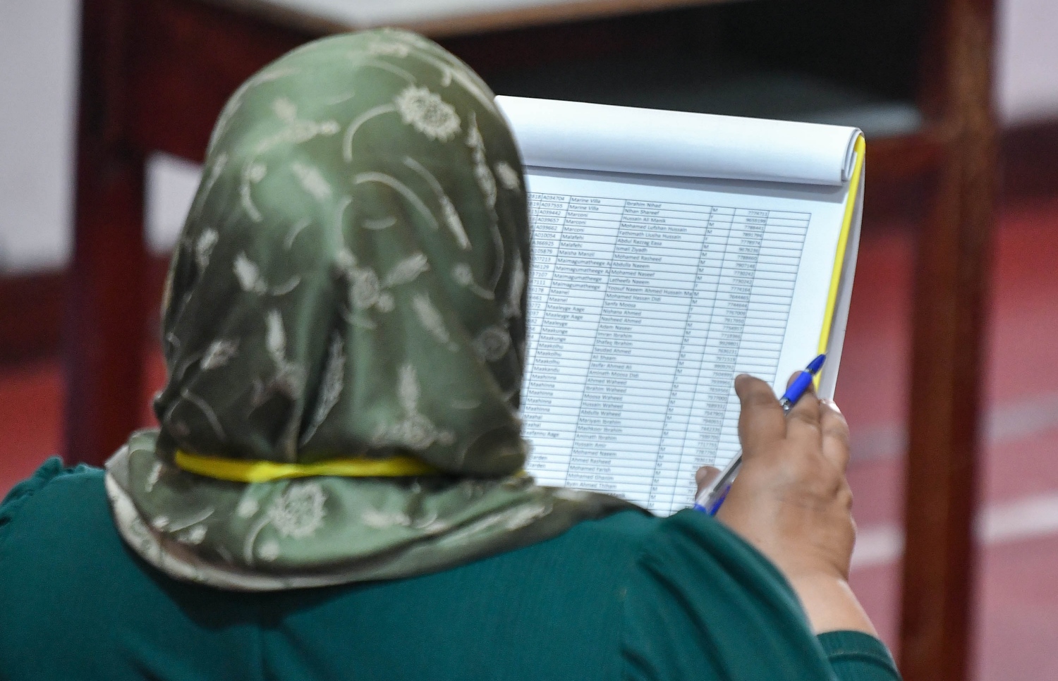 އެމްޑީޕީގެ ތާރީހުގައި ބާއްވާ އެންމެ ވާދަވެރި އެމްޑީޕީ ރިޔާސީ ޕްރައިމަރީގައި އިމާދުއްދީން ސްކޫލުގައި އޮފިޝަލަކު ވޯޓާސް ލިސްޓް ޗެކް ކުރަނީ.-- ފޮޓޯ: ފަޔާޒް މޫސާ /މިހާރު