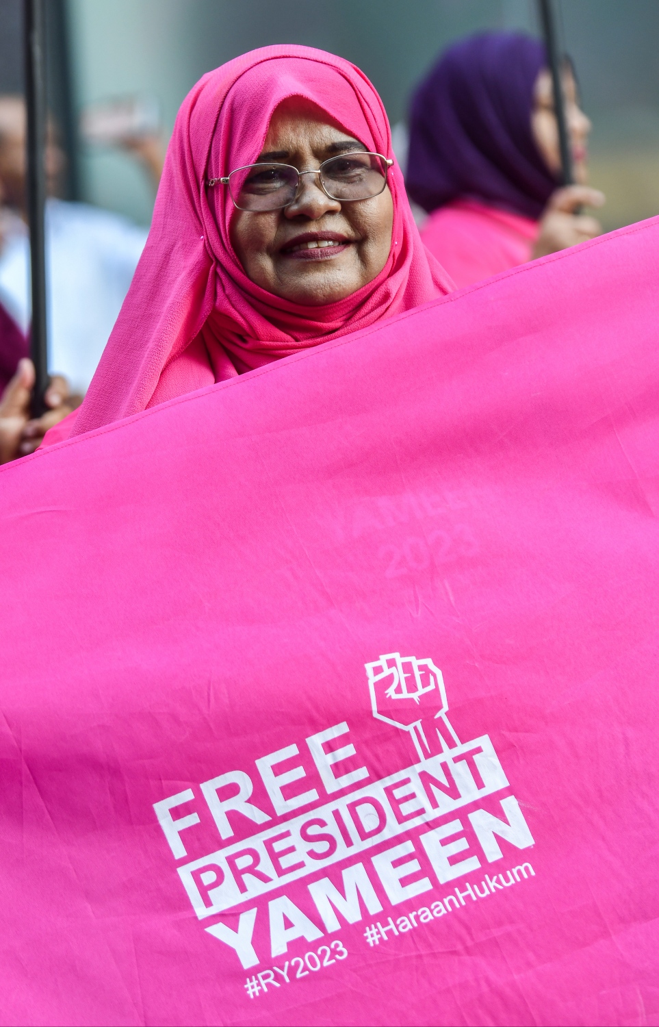 މަނީ ލޯންޑްރިން އާއި ރިޝްވަތުގެ ކުށް ސާބިތުވެ 11 އަހަރުގެ ޖަލު ހުކުމެއް ތަންފީޒުކުރައްވަމުން ގެންދަވާ ކުރީގެ ރައީސް އަބްދުﷲ ޔާމީން މިނިވަން ކުރުމަށް ގޮވާލައި ލިޔުންތައް ލިޔެފައިވާ ދިދައެއް ހިފައިގެން މިއަދުގެ ހިނގާލުމުގައި އަންހެނަކު ބައިވެރިވަނީ.--- ފޮޓޯ: ފަޔާޒު މޫސާ | މިހާރު