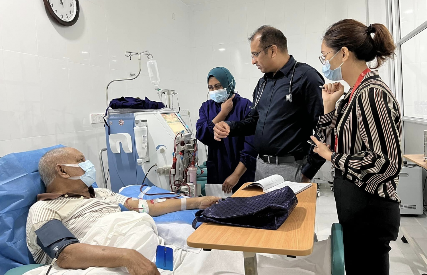 ޅ. އަތޮޅު ހޮސްޕިޓަލުގައި ޑައިލިސިސްގެ ހިދުމަތް ދޭން ފެށުމުގެ ގޮތުން ފުރަތަމަ އެ ހޮސްޕިޓަލުން އެ ފަރުވާ ހޯދާ މީހާއަށް ފަރުވާދޭއިރު ކައިރީގައި ސިއްހީ ހިދުމަތްތެރިން -- ފޮޓޯ: ޅ. އަތޮޅު ހޮސްޕިޓަލް