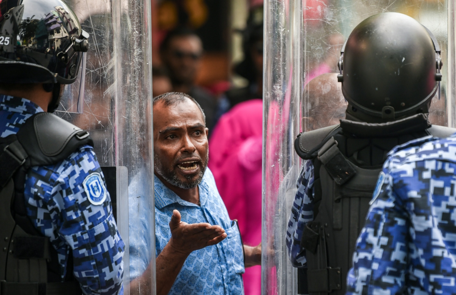 މުޒާހަރާގެ ބައިވެރިއަކު ފުލުހުންގެ ޝީލްޑް ކައިރިއަށް ގޮސް ފުލުހަކާ ވާހަކަ ދައްކަނީ.--- ފޮޓޯ: ފަޔާޒު މޫސާ | މިހާރު