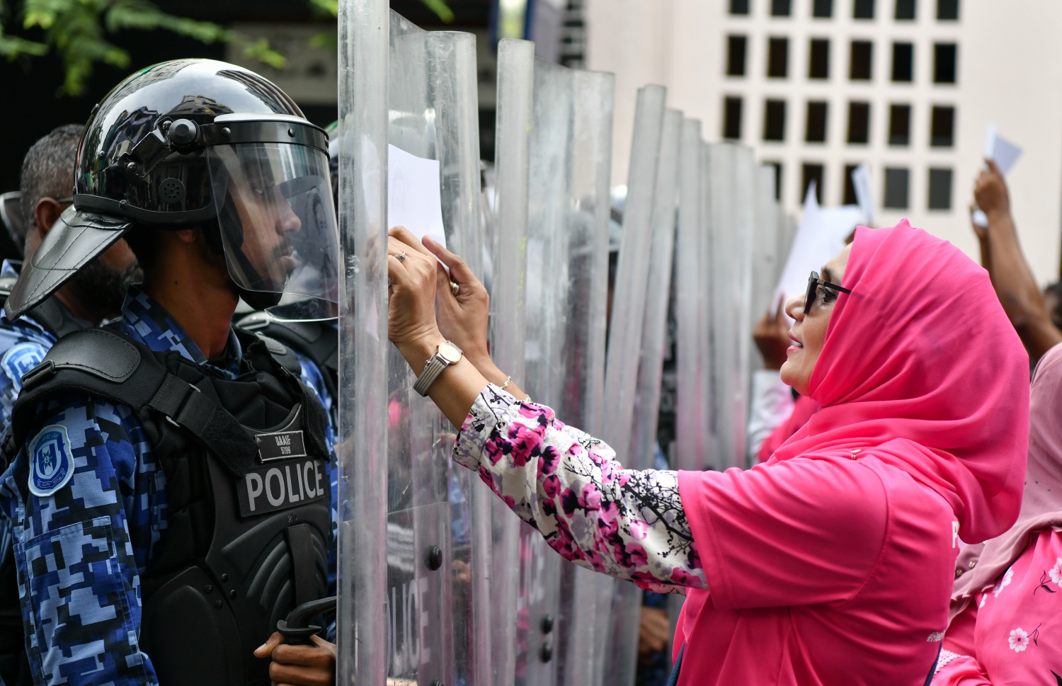 ކުރީގެ ރައީސް އަބްދުﷲ ޔާމީން ޖަލުން މިނިވަންކުރުމަށް ގޮވާލައި ލިޔެފައިވާ ކަރުދާސްގަނޑެއް ފުލުހުންގެ ޝީލްޑްގައި މުޒާހަރާގެ ބައިވެރިއަކު ތައްކުރަނީ.--- ފޮޓޯ: ފަޔާޒު މޫސާ | މިހާރު
