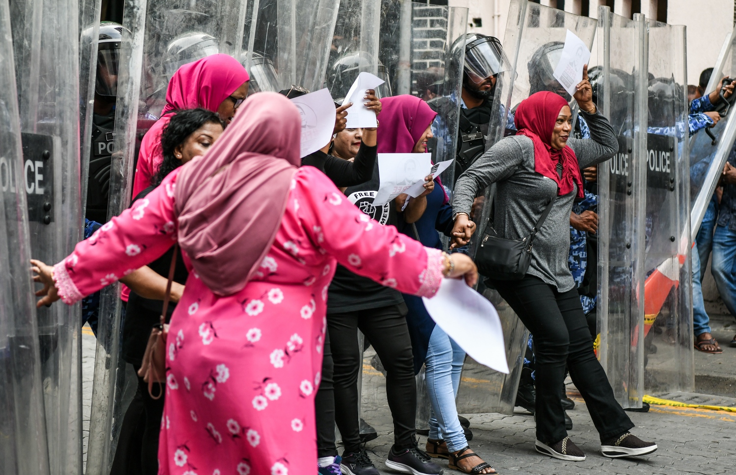 މުޒާހާރާގެ ބައިވެރިން ފަހަތަށް ޖެއްސުމަށް ފުލުހުން މަސައްކަތްކުރާއިރު، އަންހެނުންތަކެއް ފުލުހުންގެ ޝީލްޑްތަކުގައި ޖެހިގެން ކުރިއަށް ނުދެވޭނެހެން ހުރަސް އަޅަނީ.--- ފޮޓޯ: ފަޔާޒު މޫސާ | މިހާރު