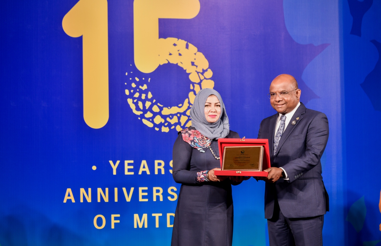 އެމްޓީޑީސީގެ 15 ވަނަ އަހަރީ ދުވަހާ ގުޅިގެން ކުރުނބާގައި ބޭއްވި ރަސްމިއްޔާތުގައި އަގު ވަޒަން ކުރުމުގެ ފިލައެއް އެމްޑީއޭގެ ނައިބު އައިޝަތު ރަފިއްޔާ އަށް(ވ) ފޮރިން މިނިސްޓަރު އަބްދުﷲ ޝާހިދު(މ) ދެއްވަނީ.-- ފޮޓޯ: ފަޔާޒް މޫސާ /މިހާރު