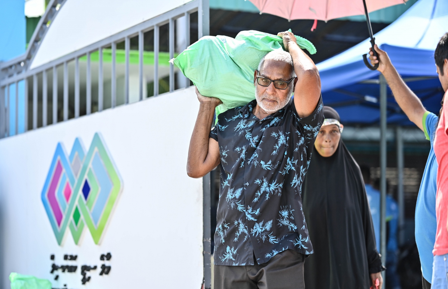 ދިވެހިންނަށް ބެހުމަށް ޗަމްޕާ ބްރަދާސްގެ ފަރާތުން ހަދިޔާކުރި ކަރަ އާއި ކާށި ލިބުނު މީހަކު، ސިޓީ ކައުންސިލްގެ އާންމު ހިދުމަތްތަކާ ބެހޭ އިމާރާތުން ނުކުންނަނީ.--- ފޮޓޯ: ނިޝާން އަލީ / މިހާރު