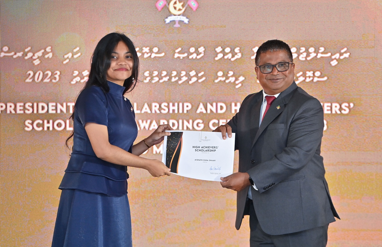 ރައީސްގެ އެވޯޑާއި ސްކޮލަޝިޕް ލިބުނު މަތީ ސާނަވީގެ ދަރިވަރުންނަށް ހަނދާނީ ލިޔުން ހަވާލުކުރުމަށް ބޭއްވި ރަސްމިއްޔާތުގައި ސްކޮލަޝިޕް ލިބުނު ދަރިވަރަކަށް ލިޔުން ހަވާލު ކުރައްވަނީ.-- ފޮޓޯ.-- ރައީސް އޮފީސް