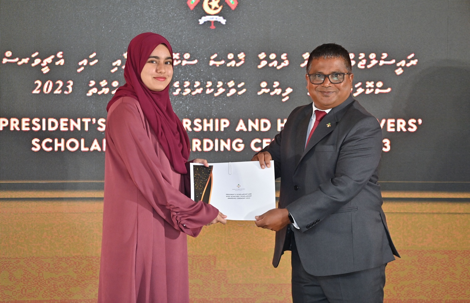 ރައީސްގެ އެވޯޑާއި ސްކޮލަޝިޕް ލިބުނު މަތީ ސާނަވީގެ ދަރިވަރުންނަށް ހަނދާނީ ލިޔުން ހަވާލުކުރުމަށް ބޭއްވި ރަސްމިއްޔާތުގައި ސްކޮލަޝިޕް ލިބުނު ދަރިވަރަކަށް ލިޔުން ހަވާލު ކުރައްވަނީ.-- ފޮޓޯ.-- ރައީސް އޮފީސް