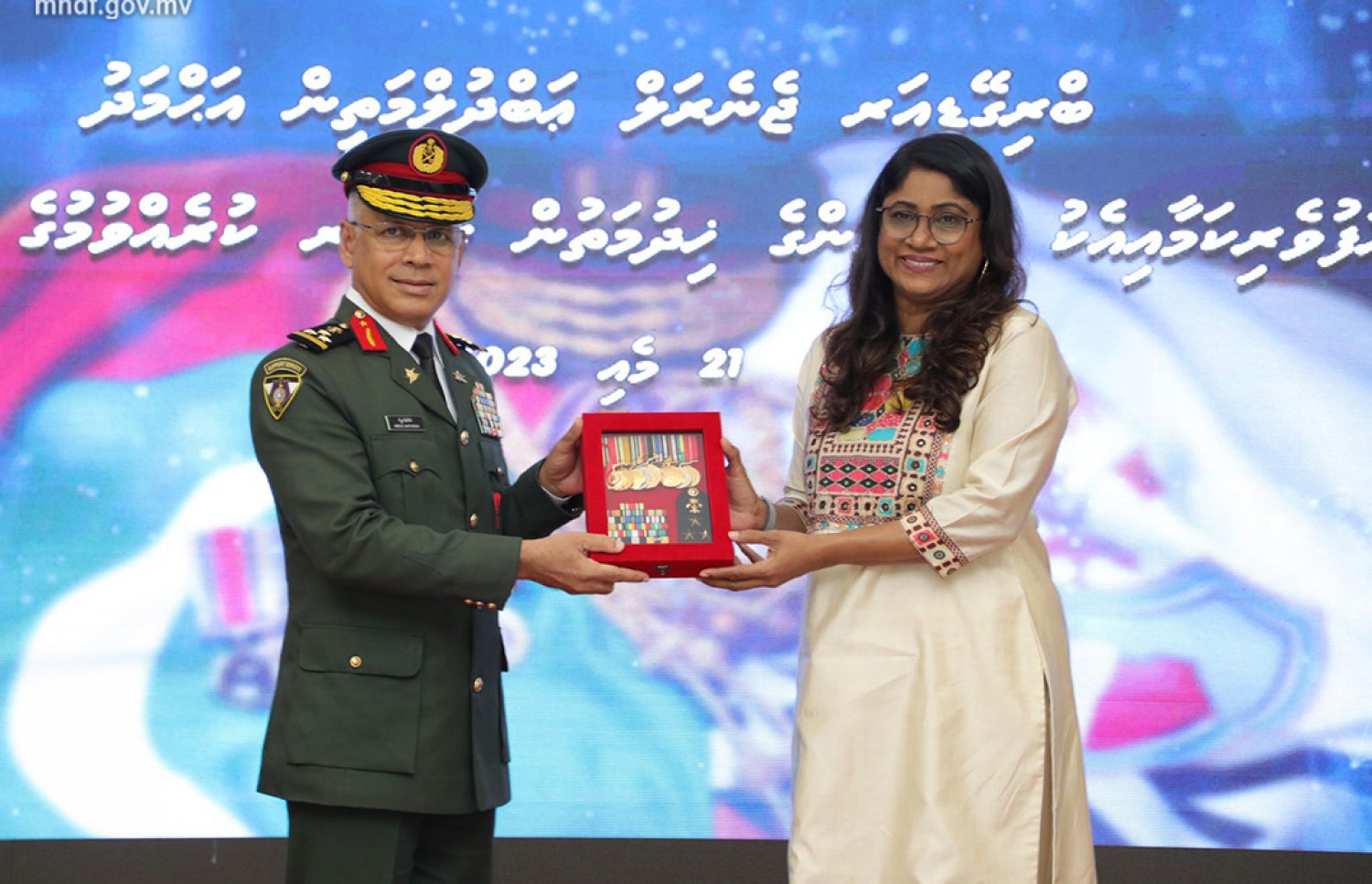 ވި ބްރިގޭޑިއާ ޖެނެރަލް އަބްދުލް މަތީން އަހުމަދު ރިޓަޔާކުރެއްވުމާ ގުޅިގެން އެމްއެންޑީއެފުން ބޭއްވި ރަސްމިއްޔާތުގައި ޑިފެންސް މިނިސްޓަރު މާރިޔާ އަހްމަދު ދީދީ އޭނާއަށް މެޑަލް ބޯޑު ހަވާލުކުރައްވަނީ.-- ފޮޓޯ: އެމްއެންޑީއެފް