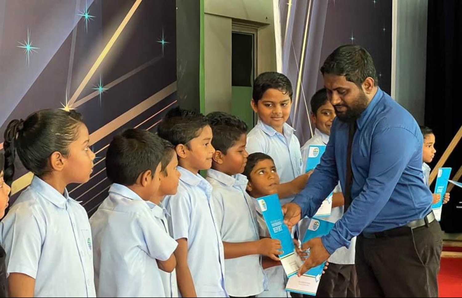 ށ. މިލަންދޫ ސްކޫލްގެ ދަރިވަރުންތަކަކަށް ރިޕޯޓް ފޯމް ހަވާލުކުރަނީ.-- ފޮޓޯ: މިލަންދޫ ސްކޫލް