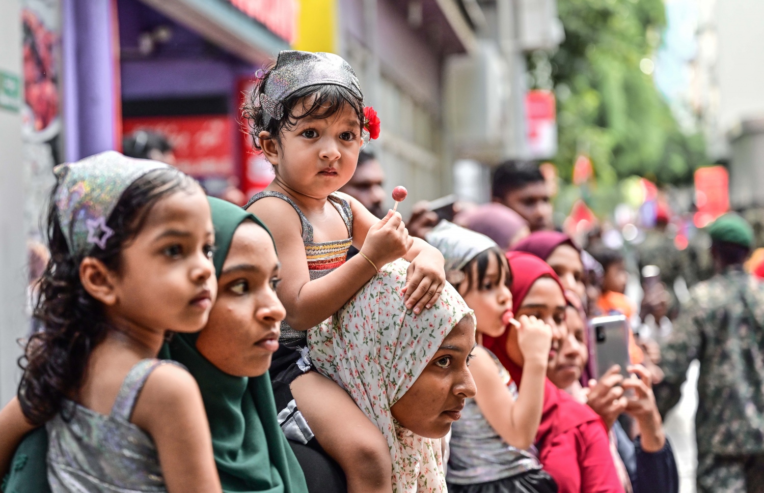 ސިފައިންގެ ޕެރޭޑް ބަލާލުމަށް ކުޑަކުދިންތަކެއް ބެލެނިވެރިންނާއެކު މަޖީދީމަގުގައި މަޑުކޮށްލައިގެން -- ފޮޓޯ: ނިޝާން އަލީ | މިހާރު