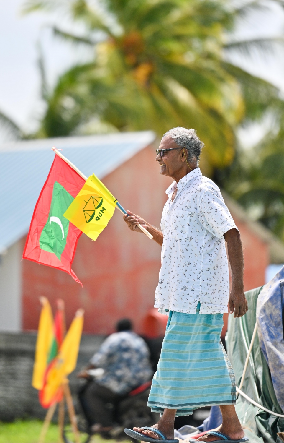 އެމްޑީޕީގެ ރިޔާސީ ކެންޑިޑޭޓް ރައީސް އިބްރާހިމް މުހައްމަދު ސޯލިހުގެ ރިޔާސީ ކެމްޕެއިނަށް ގދ. ނަޑެއްލާ އަށް ވަޑައިގަތުމުން އެ މަނިކުފާނަށް މަރުހަބާ ކިޔަން އެ ޕާޓީގެ ދިދަ ހިފައިގެން ބަނދަރުމަތީގައި ހުރި އުމުރުން ދުވަސްވީ މީހެއް.-- ފޮޓޯ: ފަޔާޒް މޫސާ | މިހާރު