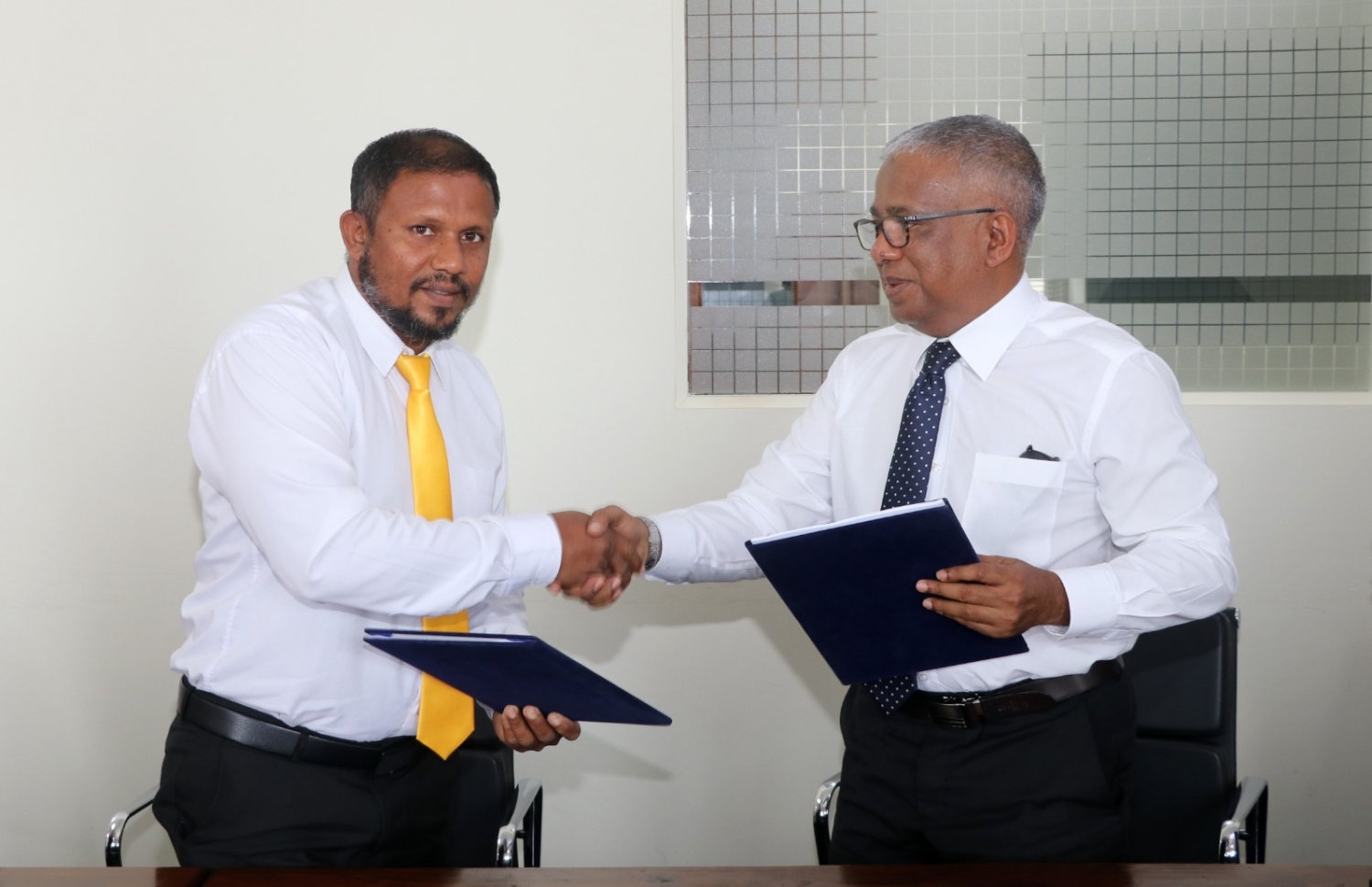 ރ. މަޑުއްވަރީ ކައިރީގައި އޮންނަ ފަޅުރަށެއް ކަމަށްވާ ރ. އުފުލަންދޫ، މަޑުއްވަރީ ކައުންސިލާ ހަވާލުކުރުމުގެ އެއްބަސްވުމުގައި ސޮއިކުރެއްވުމަށް ފަހު ސްޓޭޓް މިނިސްޓަރު އަކްރަމް ކަމާލުއްދީން އާއި ކައުންސިލް މެމްބަރު އާޔަތުﷲ ނައީމް ސަލާންކުރައްވަނީ.-- ފޮޓޯ: ޕްލޭނިން މިނިސްޓްރީ