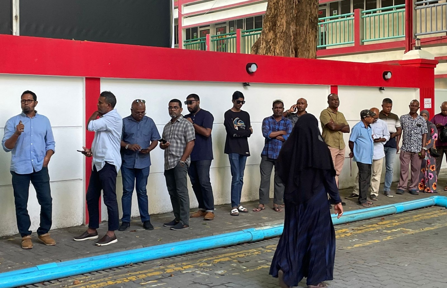 މަޖީދިއްޔާ ސްކޫލްގައި ބަހައްޓާފައިވާ ވޯޓުފޮއްޓަން ވޯޓުލާން ބަޔަކު އެ ސްކޫލްގެ ބޭރުގައި ކިއު ހަދާފައި.---ފޮޓޯ: މިހާރު