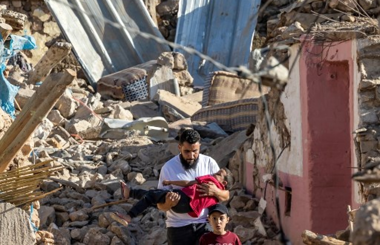 މޮރޮކޯގެ ބިންހެލުމުގައި އިމާރާތެއްގެ ދަށުން ސަލާމަތްވި މީހަކު ކުޑަ ކުއްޖަކު ގޮވައިގެން: ބާރުގަދަ އެ ބިންހެލުމުގައި 800 އަށް ވުރެ ގިނަ މީހުން މަރުވި --- ފޮޓޯ: އޭއެފްޕީ