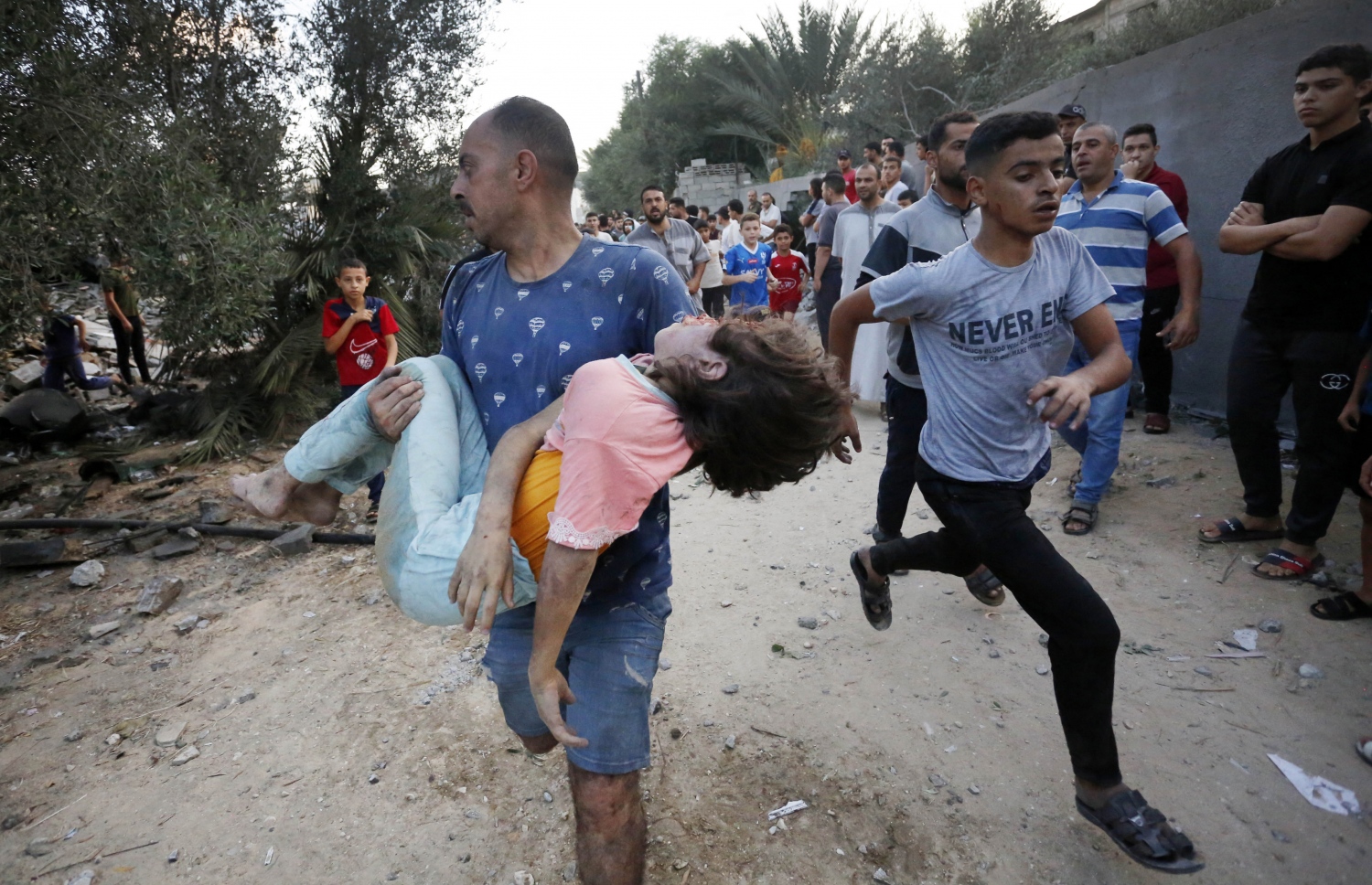 އިޒްރޭލުގެ ހަމަލާއެއްގައި ޒަހަމްވި ކުއްޖަކު ނަގައިގެން މީހަކު ގެންދަނީ.-- ފޮޓޯ: އޭއެފްޕީ