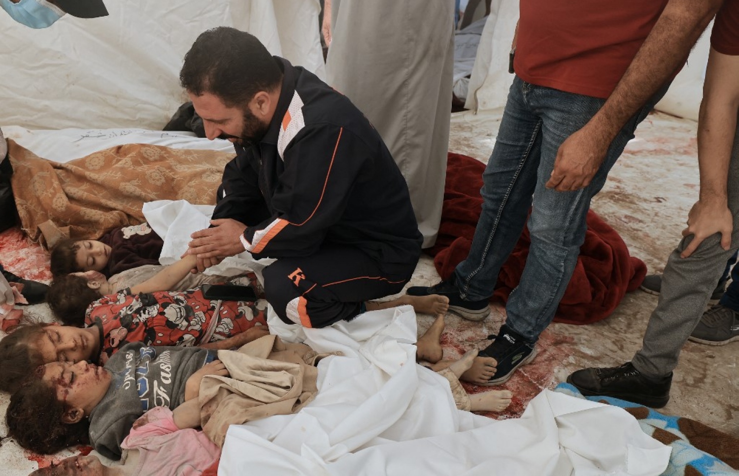 އިޒްރޭލުން ދިން ވައިގެ ހަމަލާއެއްގައި ނިޔާވި ތުއްތު ކުދިންތަކެއް ކައިރީގައި މީހަކު އިށީނދެލައިގެން އިނދެ ރޮނީ.-- ފޮޓޯ: އޭއެފްޕީ